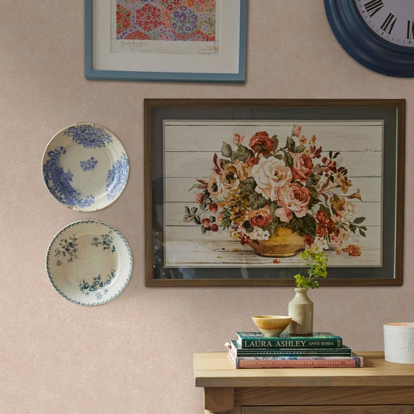 Wandgestaltung mit Bildern und Ziertellern über einem Holzmöbel mit dekorativen Objekten im klassischen Landhausstil