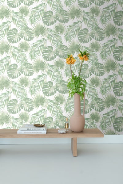 Zimmer mit grüner Blättertapete, Holztisch und Blumenvase