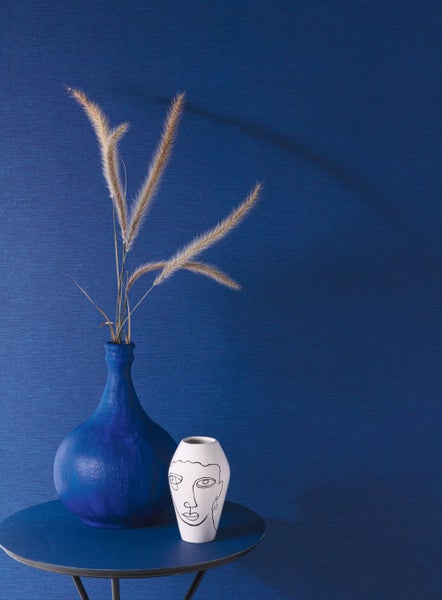 Dekorative Wandgestaltung mit floralem Tapetenmuster in einem Wohnraum mit Sofa und Teppich