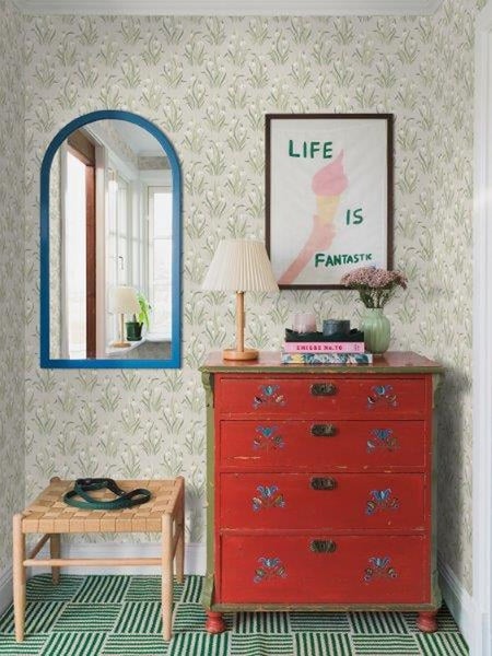 Dekoratives Interieur mit Kommode, Spiegel und Kunst an einer strukturierten Wand