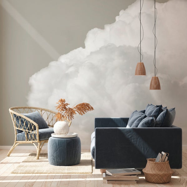 Modernes Wohnzimmer mit Wolken-Fototapete, Samtsofa, Rattan-Sessel und hellem Holzfußboden.