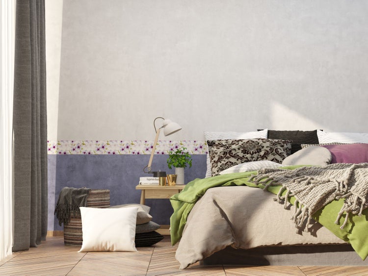Schlafzimmer mit Bett, Nachttisch und floraler Bordüre an der Wand