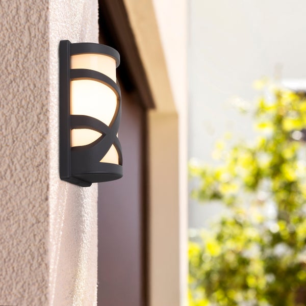 Schwarze Außenwandleuchte mit geschwungenem Design an einer Fassade.