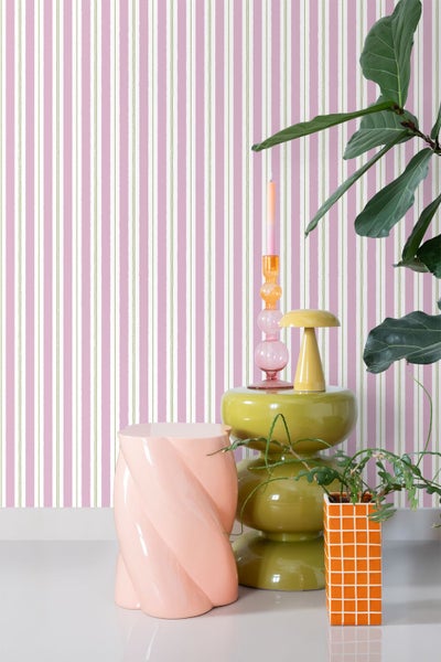 Dekoratives Interieur mit gestreifter Tapete, Beistelltisch, Pflanzen und Kerzenständer