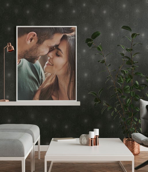 Zimmer mit gemusterter Tapete, Tisch, Vase und Büchern.