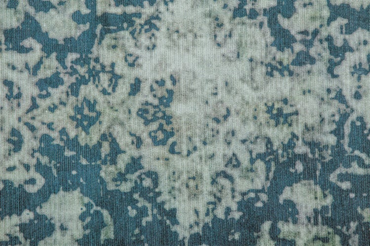 Nahaufnahme eines gewebten Teppichs in Blau und Grau mit abstraktem Muster und gerippter Textur.