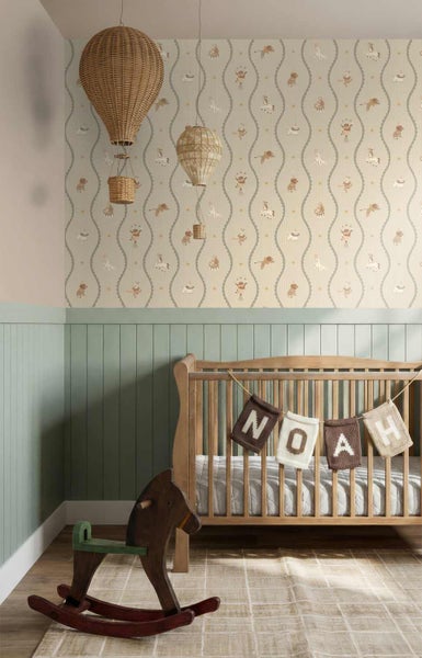Kinderzimmer mit Tiermotiv-Vliestapete, grüner Holz-Wandvertäfelung, Babybett aus Holz und dekorativen Heißluftballons aus Korbgeflecht.