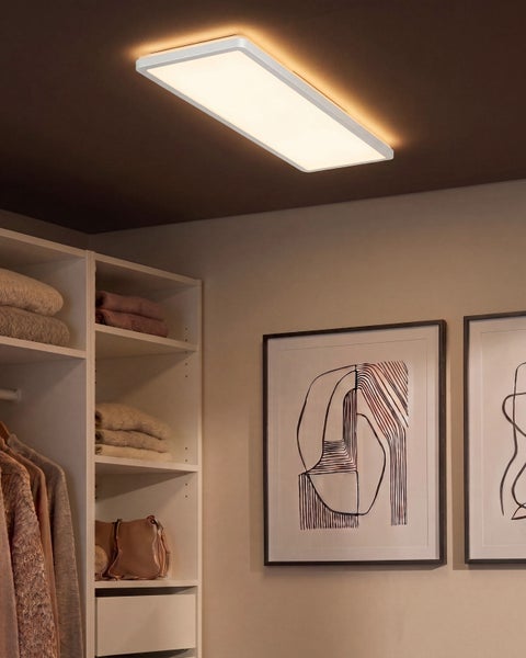 Rechteckige LED Deckenleuchte montiert an der Decke in einem Ankleidezimmer mit Regalen Kleidung und Wandbildern