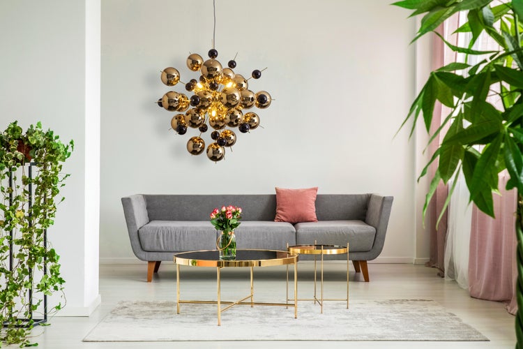 Helles Wohnzimmer mit Sofa, Tisch, Zimmerpflanzen und kugelförmiger Lampe