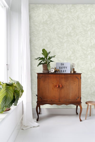 Zimmeransicht mit Holzkommode und Blattmuster-Tapete