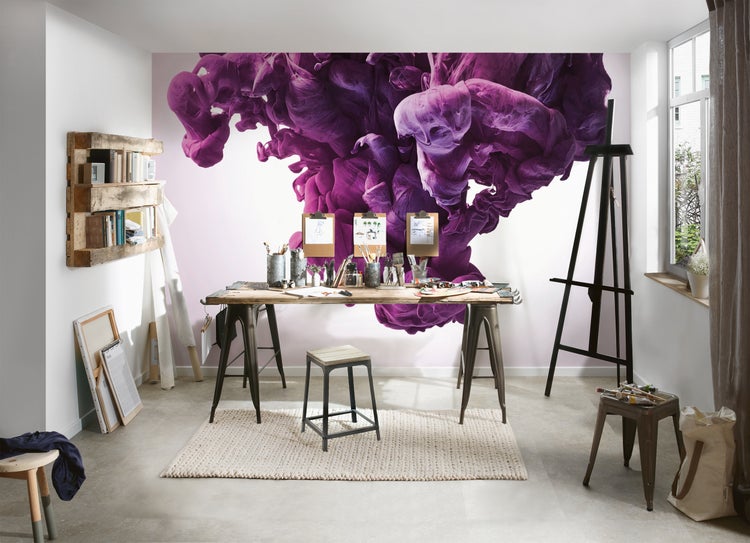 Fototapete mit abstraktem, violettem Rauch- oder Tintenmotiv in einem hellen, kreativ eingerichteten Atelier mit Holztisch und Staffelei.