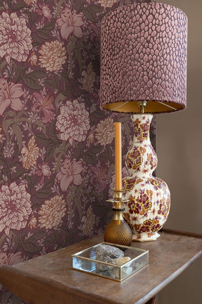 Dekorative Szene mit gemusterter Tapete, Tischlampe und Kerzenständer auf einem Tisch