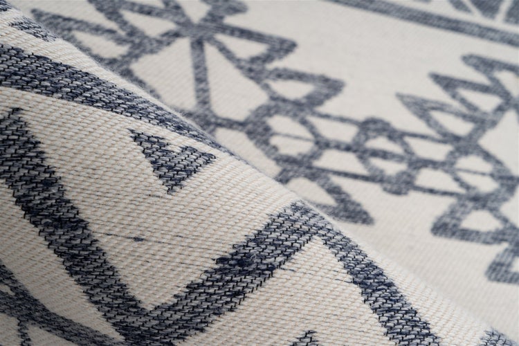 Nahaufnahme eines gewebten Teppichs mit geometrischem Muster und sichtbarer Textur.
