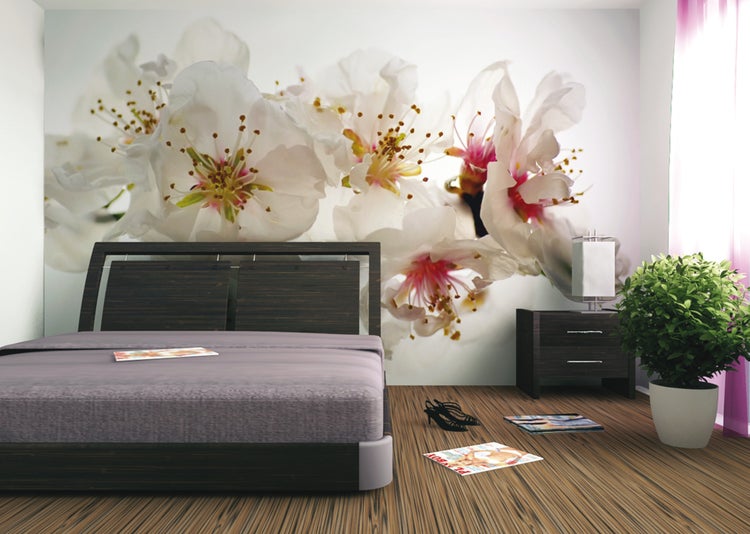 Schlafzimmer mit Doppelbett, Nachttisch, Zimmerpflanze und Fototapete mit Blütenmuster