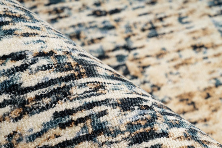 Nahaufnahme eines Teppichs mit abstraktem horizontalem Muster in Creme, Dunkelblau und Schwarz sowie weicher, gewebter Oberfläche.