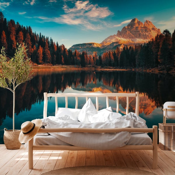 Fototapete mit Bergsee-Panorama, herbstlichem Wald und Berggipfeln in einem hellen Schlafzimmer mit Holzbett.