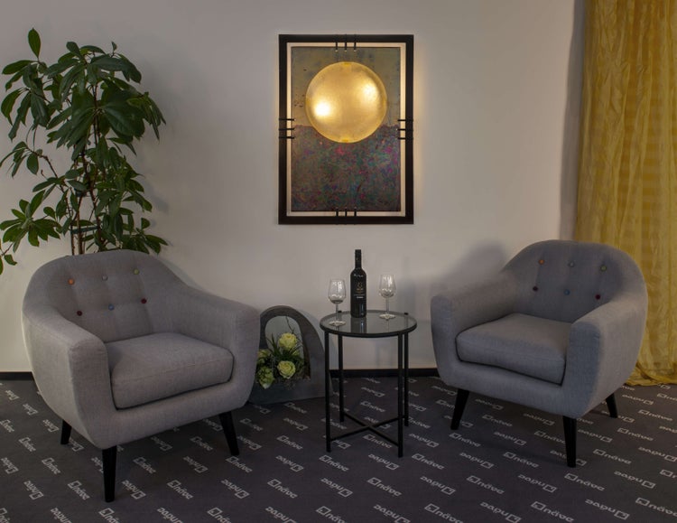 Wohnzimmer mit zwei grauen Sesseln, einem Beistelltisch mit Wein und Gläsern und einer Zimmerpflanze