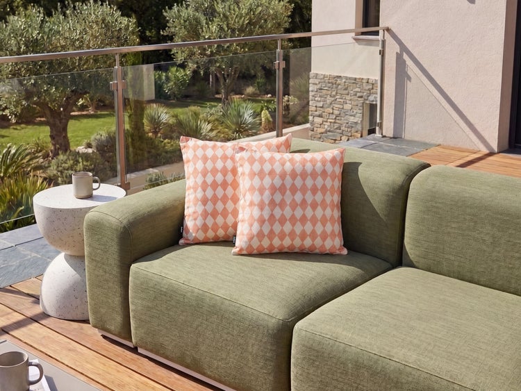 Zwei quadratische Dekokissen mit Rautenmuster auf einem modernen Outdoor Sofa auf einer Terrasse
