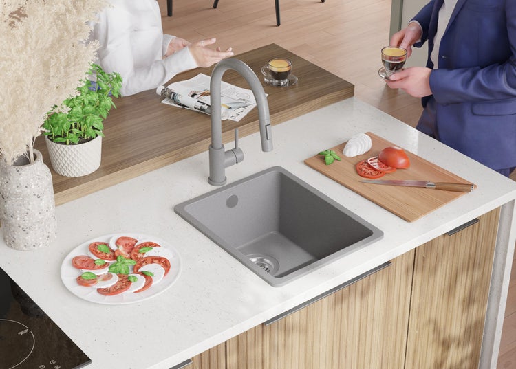 Küchenszene mit Spüle, Armatur, Kochfeld und zubereiteten Speisen auf der Arbeitsplatte.