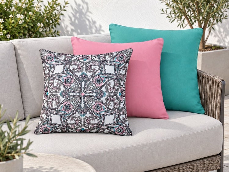 Set aus drei quadratischen Dekokissen für Gartenmöbel mit Paisley Muster und einfarbigen Bezügen auf einem Loungesofa.