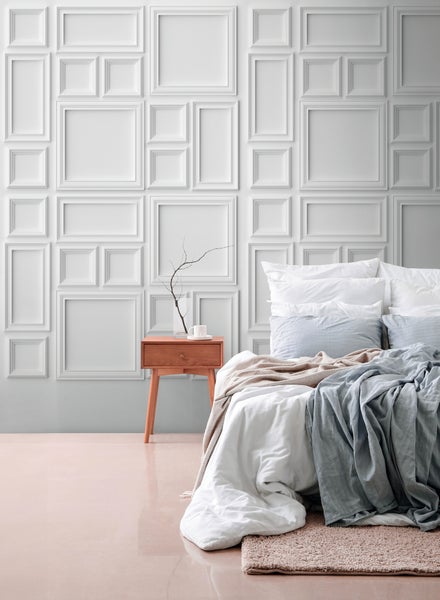 Modernes, helles Schlafzimmer mit Wandgestaltung aus geometrischen 3D-Wandpaneelen, Holz-Nachttisch und gemachtem Bett.