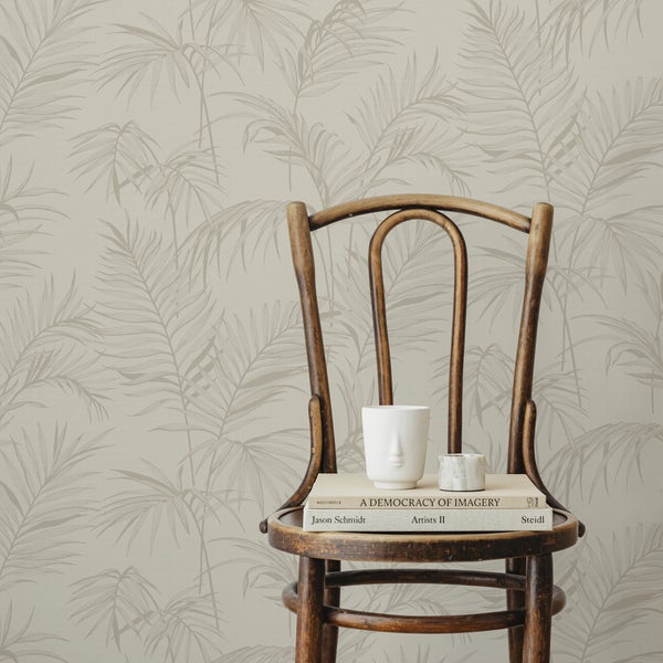 Vliestapete mit dezentem Palmwedelmuster an einer Wand hinter einem Holzstuhl mit Büchern und einer Vase.