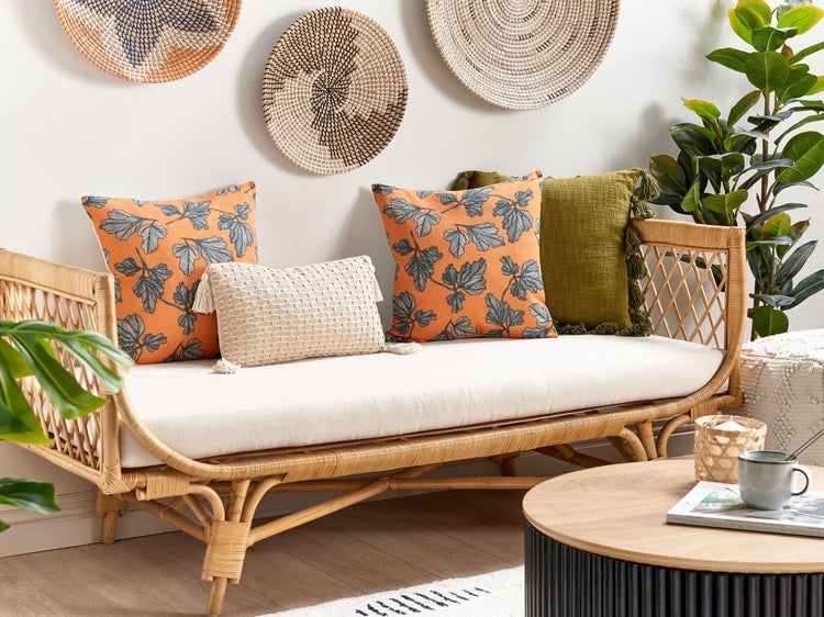 Wohnzimmer mit Rattan-Sofa, Kissen und dekorativen Wandtellern für eine gemütliche Atmosphäre.