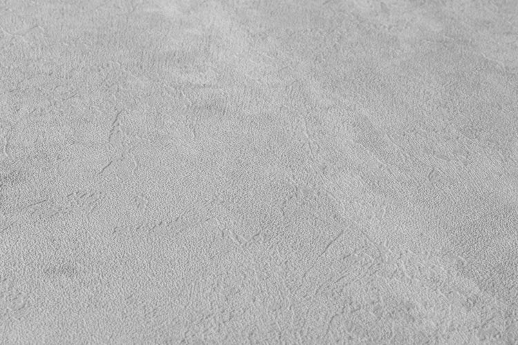 Dekoratives Interieur mit einem hellen Holztisch, einem Rahmen mit einem Schwarzweißbild, verschiedenen Gefäßen und einer strukturierten Wand im Hintergrund