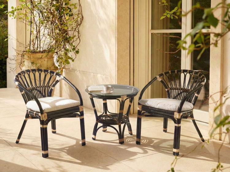 Gartenset mit zwei Korbstühlen, Sitzkissen und rundem Tisch mit Glasplatte