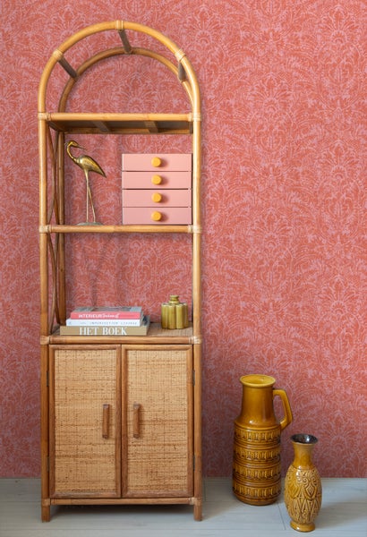 Dekoratives Interieur mit Regalsystem, Aufbewahrungsboxen und Vasen vor gemusterter Wand