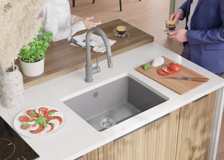 Küchenspüle mit Armatur auf einer Küchentheke mit Lebensmitteln und Personen.