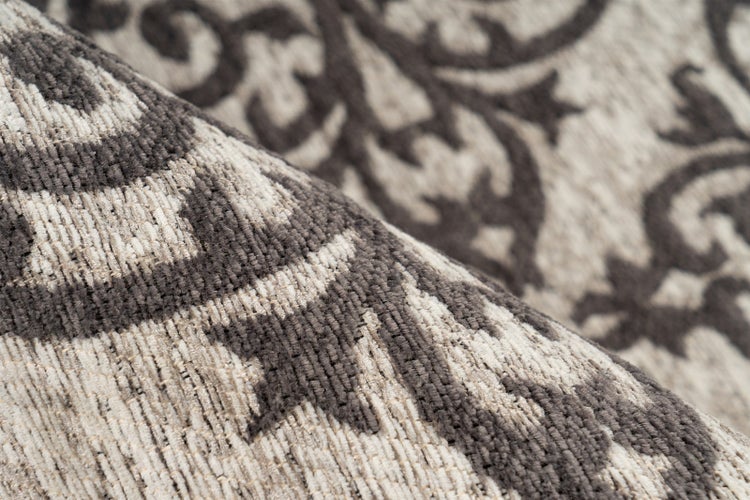 Nahaufnahme eines gewebten Teppichs mit floralem Ornamentmuster und sichtbarer Oberflächenstruktur.