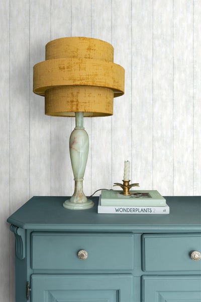 Dekorative Szene mit Tischleuchte, Kerze, Büchern und Kommode