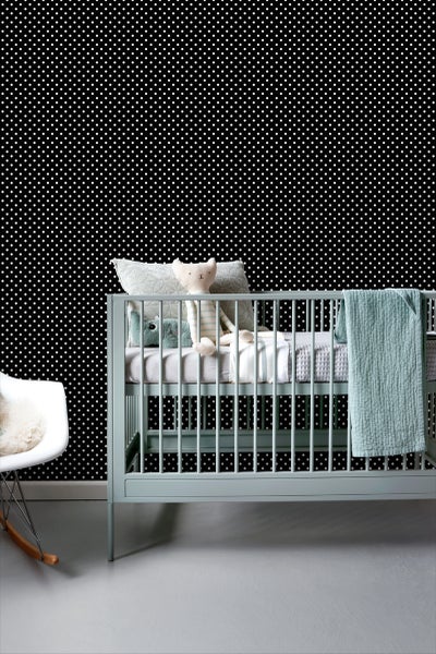 Babyzimmer mit Kinderbett und gepunkteter Tapete