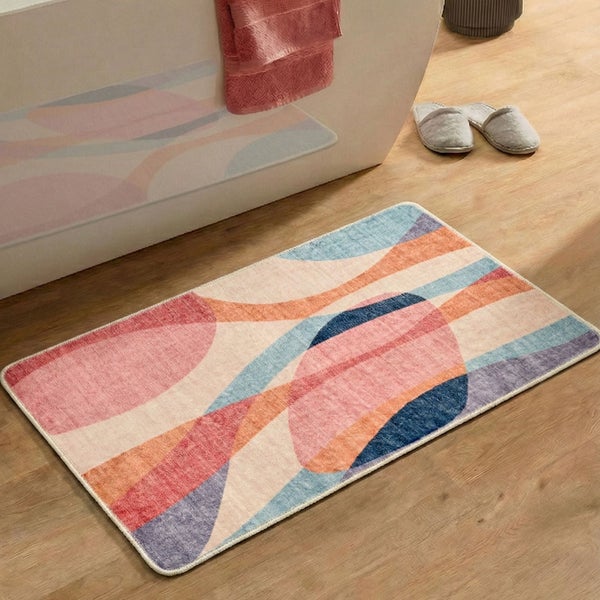 Rechteckige Badematte mit abstraktem, buntem Muster auf Holzfußboden vor einer weißen Badewanne.