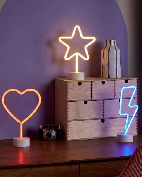 Drei LED-Neon-Tischleuchten in Form eines Herzens, Sterns und Blitzes auf einem Holzschreibtisch mit einem Holz-Organizer und einer Kamera.