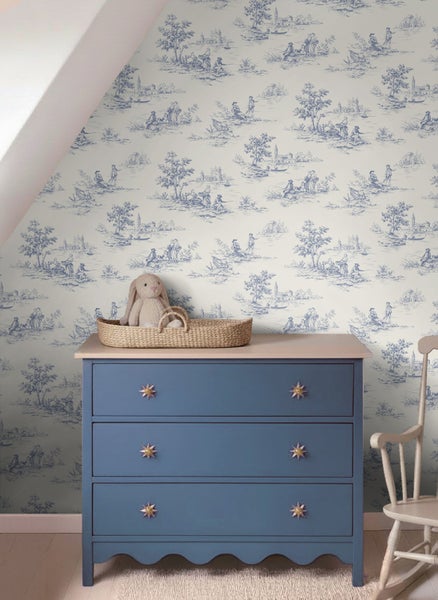 Tapete mit Toile-de-Jouy-Muster in einem hellen Zimmer mit blauer Kommode und Schaukelstuhl.