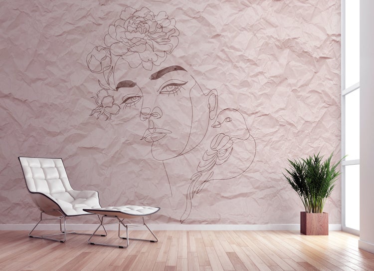 Modernes Zimmer mit großem Line-Art-Wandbild eines Frauengesichts auf Knitterpapier-Optik, weißem Loungesessel und Parkettboden.