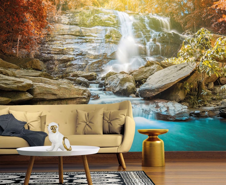 Fototapete mit einem Waldwasserfall, der in ein blaues Becken stürzt, in einem Wohnzimmer mit beige Sofa und Couchtisch.