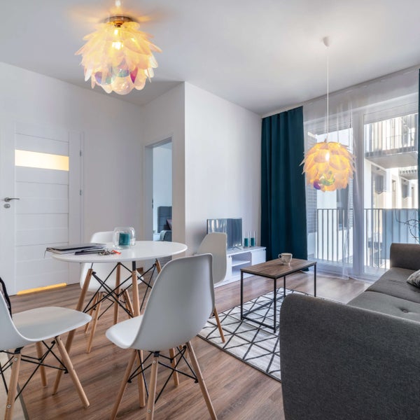 Heller Wohnraum mit Esstisch, Stühlen, Sofa und Deckenleuchten