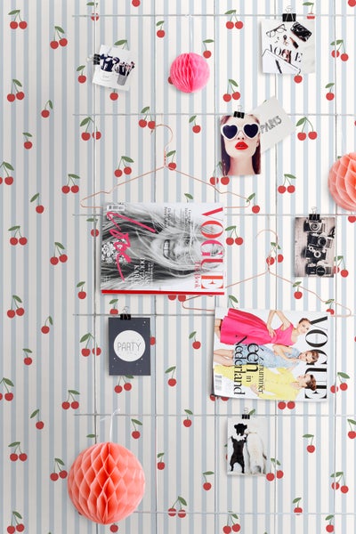 Wandgestaltung mit Kirschmuster-Tapete, Magazinen, Fotos und Dekorationen an einem Drahtgitter