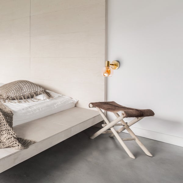 Schlafzimmer mit Bett, Hocker und Wandleuchte