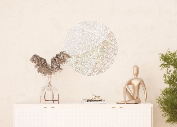 Dekorative Wohnraumgestaltung mit Wandbild, Vase, Trockenblumen und goldener Skulptur auf einem Schrank