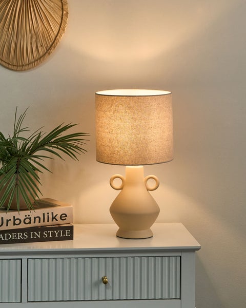 Dekorative Tischleuchte auf Kommode mit Pflanze und Büchern