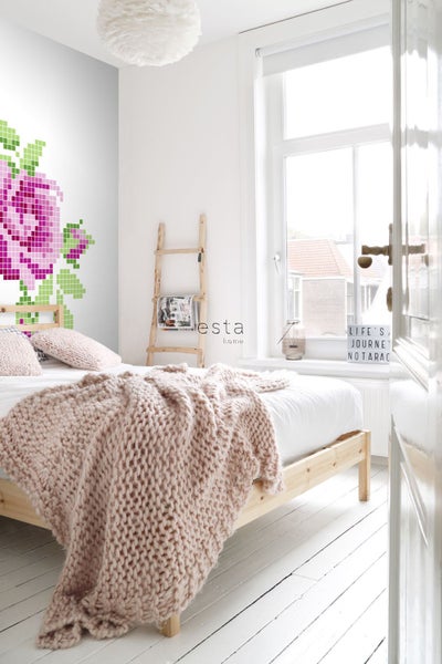 Schlafzimmer mit Bett, Strickdecke, Leiterregal und floralem Wandtattoo