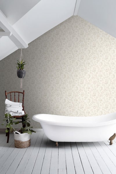 Helles Badezimmer unter einer Dachschräge mit floraler Mustertapete, freistehender Badewanne und Holzstuhl mit weißen Handtüchern.