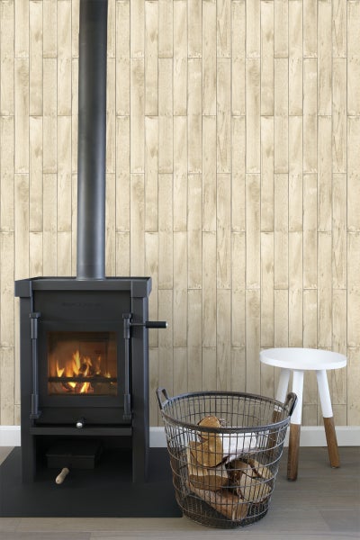 Wohnzimmer mit Kaminofen, Holzkorb und kleinem Hocker vor einer Holzwand