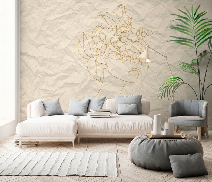 Modernes Wohnzimmer mit einer großen Wandtapete, die ein goldenes Line-Art-Porträt auf zerknitterter Papierstruktur zeigt.