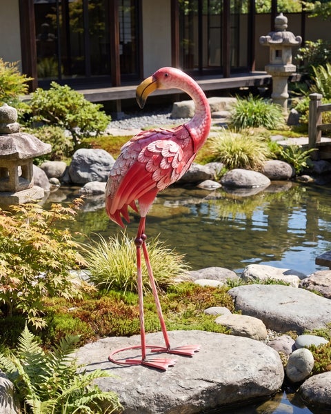 Flamingo Gartenfigur aus Metall in einem hellen japanischen Garten an einem Teich mit Steinlaterne.