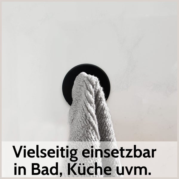 Runder, schwarzer Handtuchhaken mit grauem Handtuch, vielseitig einsetzbar in Bad und Küche.